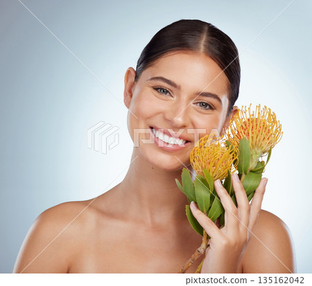 Face, skincare and happy woman with flowers in studio isolated on a white background. Portrait, natural and female model with floral pincushion protea plants for makeup, cosmetics or beauty treatment 135162042