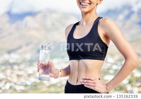 Woman is outdoor with water bottle, exercise and break after training, health and hydration with mockup space. Female athlete smile, fitness and workout in nature with h2o drink, minerals and liquid 135162339