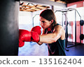 Punching bag, man and boxing in gym for exercise, workout or training for fight. Boxer, sports and serious fitness athlete punch for challenge, competition or exercising body for martial arts power. 135162404