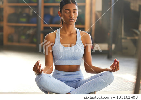 Meditation, yoga and Indian woman in gym for mindfulness, wellness and breathing exercise on floor. Mental health, meditate and female person in lotus pose for mindset, zen and balance in training Meditation, yoga and Indian woman in gym for mindfulness, wellness and breathing exercise on floor. Mental health, meditate and female person in lotus pose for mindset, zen and balance in training 135162408