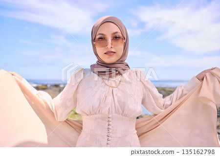 Portrait, fashion or religion with an arab woman outdoor in sunglasses and a scarf for contemporary style. Muslim, faith and dress with a trendy young islamic person posing outside in modern clothes 135162798