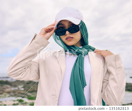 Portrait, fashion or sunglasses with an islamic woman outdoor in a cap and scarf for contemporary style. Muslim, faith or hijab for religion with a trendy young arab person outside in modern clothes Portrait, fashion or sunglasses with an islamic woman outdoor in a cap and scarf for contemporary style. Muslim, faith or hijab for religion with a trendy young arab person outside in modern clothes 135162813