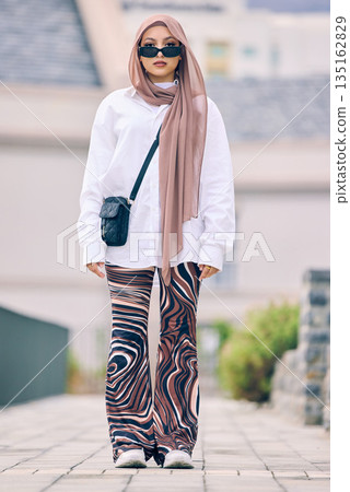 Portrait, fashion or faith with an islamic woman outdoor in a cap and scarf for contemporary style. Islam, faith and hijab with a full length trendy young muslim person outside in modern clothes Portrait, fashion or faith with an islamic woman outdoor in a cap and scarf for contemporary style. Islam, faith and hijab with a full length trendy young muslim person outside in modern clothes 135162829