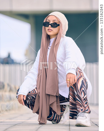 Portrait, fashion or religion with a muslim woman in the uae wearing a hijab and scarf for contemporary style. Islam, faith and burka with a trendy young islam person outside in traditional clothes Portrait, fashion or religion with a muslim woman in the uae wearing a hijab and scarf for contemporary style. Islam, faith and burka with a trendy young islam person outside in traditional clothes 135162843