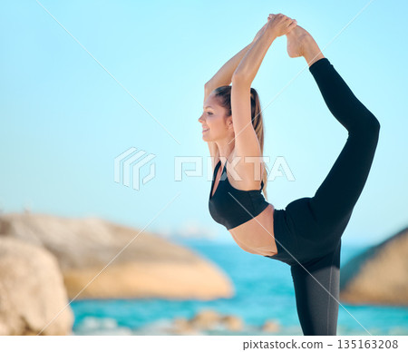 Yoga, woman and stretching body on the beach for exercise, training or wellness in nature on blue sky. Female athlete, stretch and outdoor workout with ocean, sea or waves for calm, peace or balance 135163208