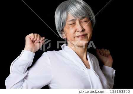 頭髮花白的老婦人伸展身體，張開肩胛骨。 135163390