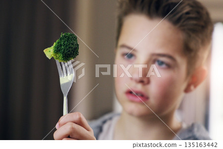 Disgust, food and refuse with child and broccoli for nutrition, health and cooking. Sad, angry and dinner with boy and green vegetable on fork at home for eating problem, frustrated and dislike 135163442