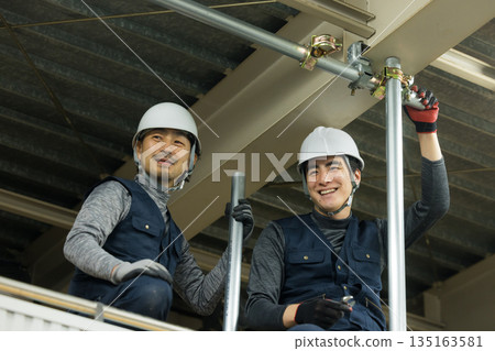 Workers assembling single-tube pipes at a factory site Workers assembling single-tube pipes at a factory site 135163581