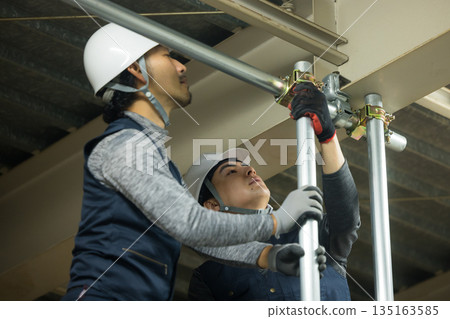 工人們在工廠工地組裝單管管道 工人們在工廠工地組裝單管管道 135163585
