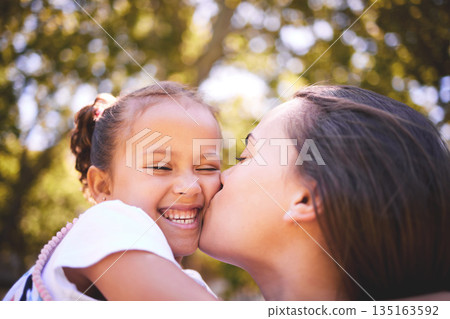 Girl, mother and kiss cheek in nature, funny and bonding on summer holiday vacation. Mom, kissing and happy child, love and affection, care and enjoying quality family time together outdoor in park. Girl, mother and kiss cheek in nature, funny and bonding on summer holiday vacation. Mom, kissing and happy child, love and affection, care and enjoying quality family time together outdoor in park. 135163592