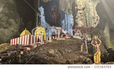 This is cave diorama features golden temples, ritual figures, and natural rock textures, blending Hindu symbolism in Batu Cave inside 135163703
