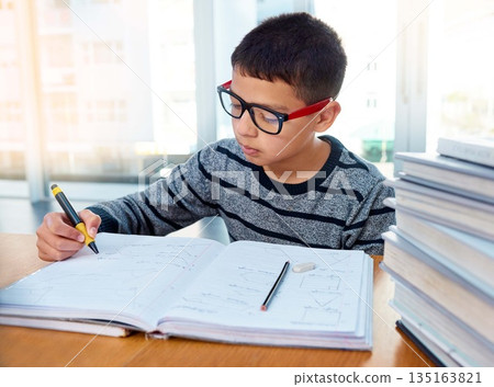 Boy child, student and writing for studying, homework or learning in education with book on table at home. Smart little kid busy on mathematics, textbooks or problem solving for study in living room Boy child, student and writing for studying, homework or learning in education with book on table at home. Smart little kid busy on mathematics, textbooks or problem solving for study in living room 135163821