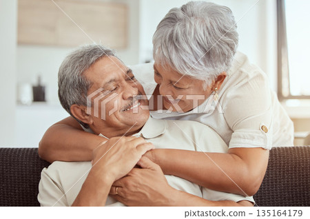 Love, hug and elderly couple on a sofa, happy and relax, laughing and talking their home together. Embrace, smile and senior man with woman on couch in a living room, cheerful and enjoying retirement 135164179