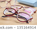 Multiple pairs of stylish red glasses for vision correction and eye care, with a blue case in the background. 135164914