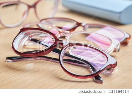 Multiple pairs of stylish red glasses for vision correction and eye care, with a blue case in the background. 135164914
