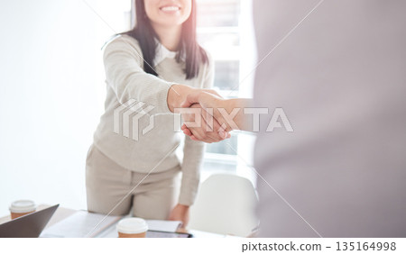 Business people, staff and handshake in a meeting, cooperation and partnership with teamwork. Closeup, woman and coworkers shaking hands, collaboration or agreement with welcome, support or thank you 135164998