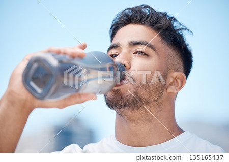 Man, fitness and drinking water in city for sustainability after running exercise, workout or training outdoors. Thirsty male person, athlete or runner with drink for hydration, rest or break in town 135165437