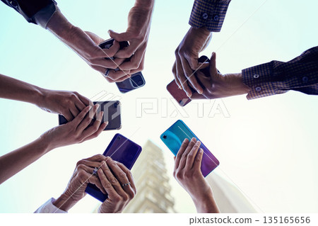 Business people, hands and circle with phone, connectivity and social media in the city. Below, sky and group with hands holding mobile in urban town with internet, web and career app with diversity Business people, hands and circle with phone, connectivity and social media in the city. Below, sky and group with hands holding mobile in urban town with internet, web and career app with diversity 135165656