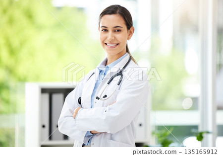 Portrait, healthcare and arms crossed with a doctor woman in the hospital for insurance or treatment. Medical, happy or smile with a young female medicine professional standing alone in a clinic 135165912