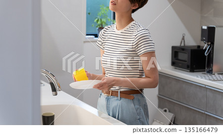 Woman washing dishes in the kitchen Woman washing dishes in the kitchen 135166479