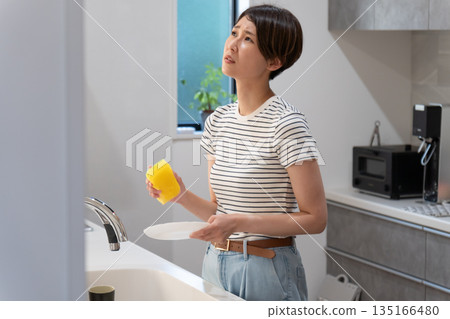 Woman washing dishes in the kitchen Woman washing dishes in the kitchen 135166480