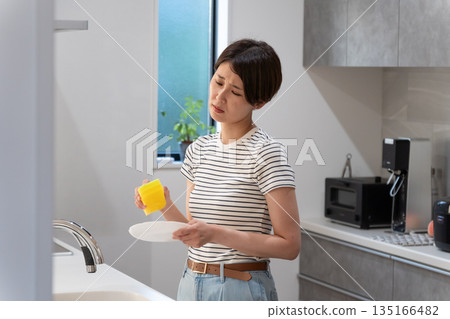 Woman washing dishes in the kitchen Woman washing dishes in the kitchen 135166482