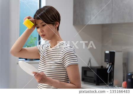 Woman washing dishes in the kitchen 135166483