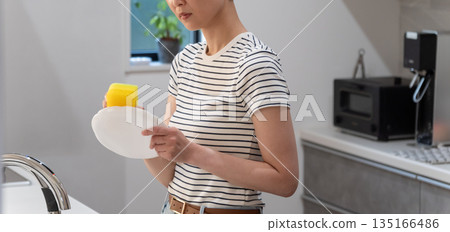 Woman washing dishes in the kitchen Woman washing dishes in the kitchen 135166486