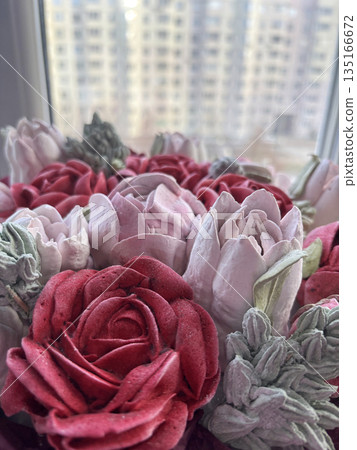 Marshmallow flowers of different colors close-up. Against a window background. The work of a marshmallow manufacturer entrepreneur. Marshmallow flowers of different colors close-up. Against a window background. The work of a marshmallow manufacturer entrepreneur. 135166672