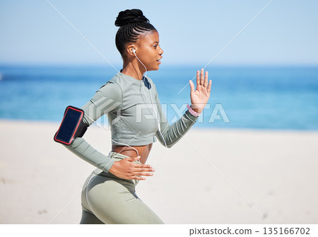 Fitness, beach and woman running, listening to music, exercise podcast or training, cardio and health technology. Ocean, focus and african person, runner or athlete workout, training and phone audio 135166702