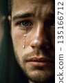 Close-up of a young man with a tear running down his cheek 135166712