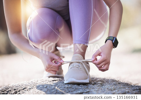 Woman, hands and tie shoes for running, exercise or workout on asphalt road or street outdoors. Hand of female person or runner tying shoe getting ready for walk, run or fitness exercising in nature 135166931