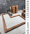 Contour of a heating stove with a bench. Laid out of brick on a concrete screed. 135166958