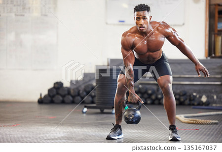 Black man, fitness and weightlifting with kettlebell for workout, exercise or training at the gym. African male person or muscular bodybuilder lifting weight for strength sports or intense exercising 135167037