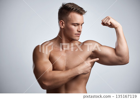 Man, bodybuilder and pointing to bicep in studio, background and exercise for muscular power. Strong, sexy and topless male model, sports athlete and flex arm muscle with pride of fitness results Man, bodybuilder and pointing to bicep in studio, background and exercise for muscular power. Strong, sexy and topless male model, sports athlete and flex arm muscle with pride of fitness results 135167119