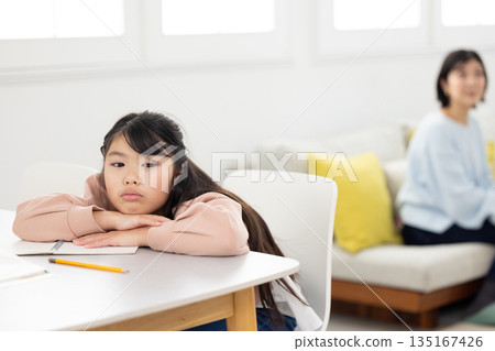一個表情悲傷的小學生女孩躺在桌上 135167426