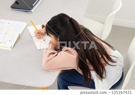 Elementary school girl studying with bad posture Elementary school girl studying with bad posture 135167431
