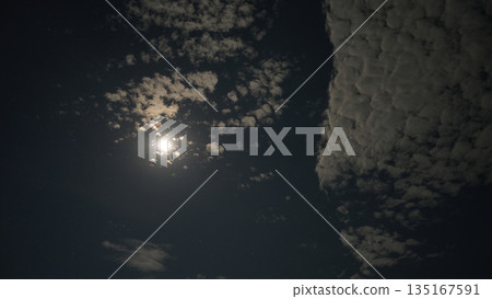 Bright moon shining through scattered clouds at night Bright moon shining through scattered clouds at night 135167591