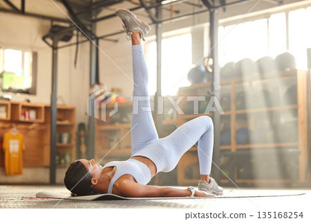 Fitness, gym or girl doing leg raise exercise, workout and training for abs or bodybuilding sports. Bodybuilder, athlete or healthy woman lifting legs up with focus, strong core muscles or wellness Fitness, gym or girl doing leg raise exercise, workout and training for abs or bodybuilding sports. Bodybuilder, athlete or healthy woman lifting legs up with focus, strong core muscles or wellness 135168254