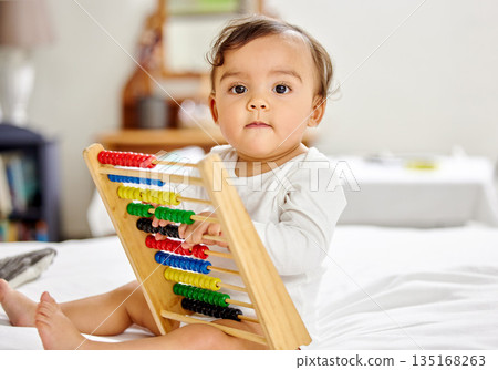 Abacus, bed and portrait of baby with toy for learning, child development and motor skills. Family home, newborn and face of adorable child with educational toys, counting beads and fun in bedroom Abacus, bed and portrait of baby with toy for learning, child development and motor skills. Family home, newborn and face of adorable child with educational toys, counting beads and fun in bedroom 135168263