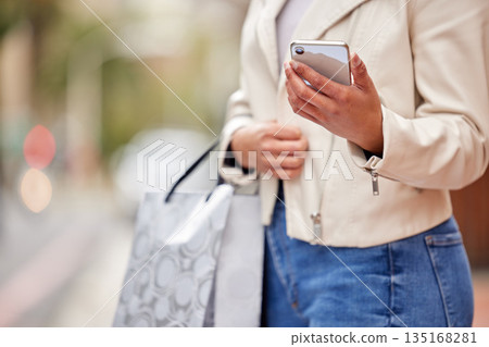 Phone, woman hands and shopping bags in city with retail sale and discount at a fashion store. Female person, urban and street with a mobile, ecommerce and social media with stores bag in town Phone, woman hands and shopping bags in city with retail sale and discount at a fashion store. Female person, urban and street with a mobile, ecommerce and social media with stores bag in town 135168281