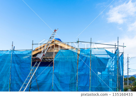 圖：一台瓦片提昇機正在將屋頂瓦片提升到一棟新建的木屋上。 135168433