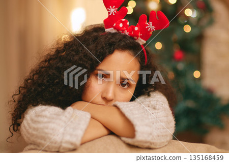 Portrait, sad woman and depression on Christmas in home with anxiety, worry and emotional crisis. Face of lonely female person feeling unhappy, bored and disappointed in festive holiday with headband 135168459