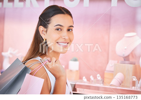 Jewelry store, window and a woman with a shopping bag in mall for fashion, sale or discount deal. Female person or customer portrait with a smile at retail shop with diamonds, jewellery and promotion Jewelry store, window and a woman with a shopping bag in mall for fashion, sale or discount deal. Female person or customer portrait with a smile at retail shop with diamonds, jewellery and promotion 135168773