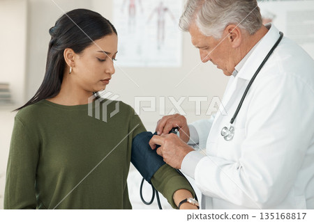 Medical, blood pressure and mature doctor with a patient for a consultation in the hospital. Medicine, equipment and healthcare worker checking hypertension of a woman at a checkup in medicare clinic 135168817