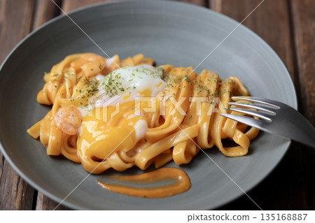 A rich shrimp cream pasta with flat noodles topped with a crumbled soft-boiled egg A rich shrimp cream pasta with flat noodles topped with a crumbled soft-boiled egg 135168887