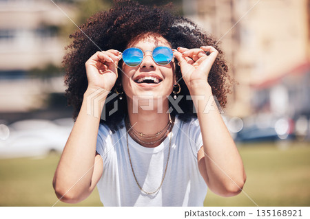 Woman, fashion and sunglasses outdoor in city for happiness, summer and travel holiday. Face of african person with natural hair or afro at nature park with glasses and positive mindset for freedom 135168921