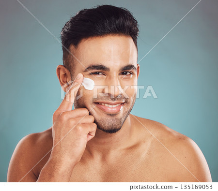 Portrait, skincare and cream with a man in studio on a gray background to apply antiaging facial treatment. Face, beauty and lotion with a young male person indoor for wellness or aesthetic self care 135169053