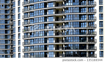 Building with blue windows in modern city landscape. Urban skyscraper exterior with geometric Building with blue windows in modern city landscape. Urban skyscraper exterior with geometric 135169344