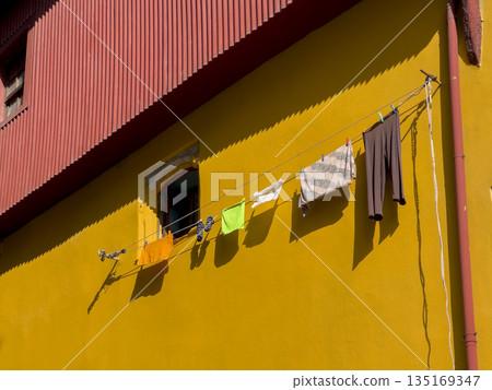 Building with home facades and clothes drying. Clean fabric textiles hanging on clothes line in Building with home facades and clothes drying. Clean fabric textiles hanging on clothes line in 135169347